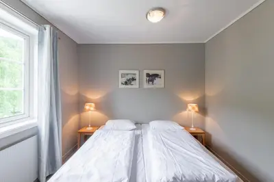 a white bedroom with two beds and two lamps at Nermo Hotel & Apartments in Hafjell
