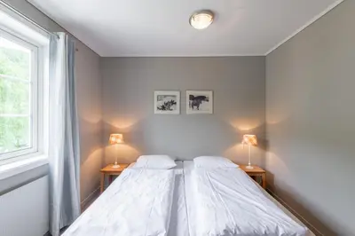 a white bedroom with two beds and two lamps at Nermo Hotel & Apartments in Hafjell