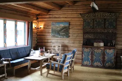 a dining room with a table and chairs and a wooden wall at Øigardseter Fjellstue in Høvringen