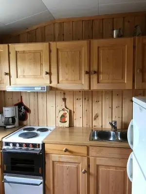 a kitchen with wooden cabinets and a stove and a sink at Øigardseter Fjellstue in Høvringen