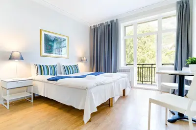 a white bedroom with a large bed and a window at Slottet Apartments in Tysso