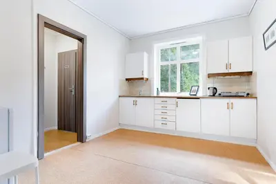 an empty kitchen with white cabinets and a window at Slottet Apartments in Tysso