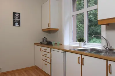 a kitchen with white cabinets and a sink and a window at Slottet Apartments in Tysso