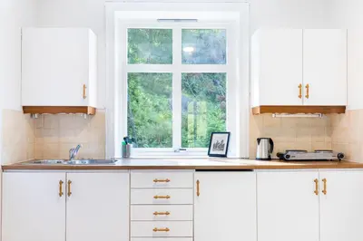 a kitchen with white cabinets and a window at Slottet Apartments in Tysso
