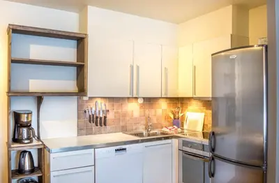 a kitchen with white cabinets and a stainless steel refrigerator at Geilolia Ferieleiligheter in Geilo