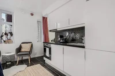 a kitchen with white cabinets and a chair in a room at LS Apartments in Bergen