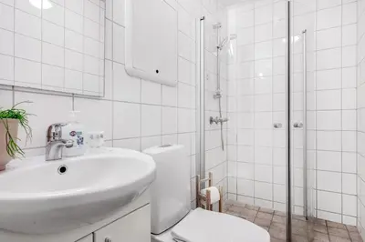a white bathroom with a sink and a shower at LS Apartments in Bergen