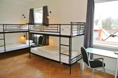a room with four bunk beds and a chair and a window at City Hostel Bergen in Bergen