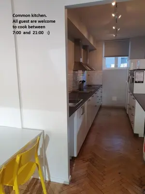 a kitchen with white cabinets and a yellow chair in it at City Hostel Bergen in Bergen