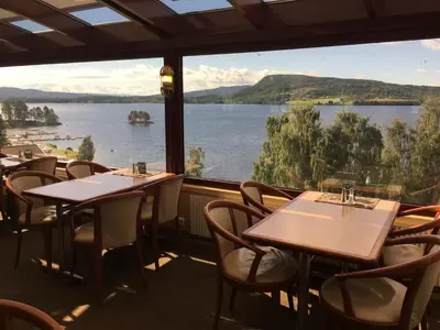 a restaurant with tables and chairs and a view of a lake at Kroderen Kro & motel AS in Hamremoen