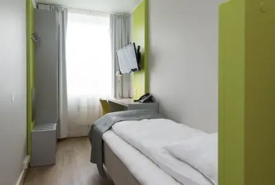 a small bedroom with a bed and a window at Thon Hotel Trondheim in Trondheim