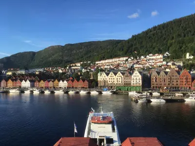 a boat in a body of water with houses and buildings at Apartment with Beautiful View to Bryggen in Bergen