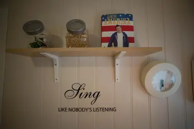 a shelf with a book and a clock on a wall at Apartment at Ranheim in Trondheim