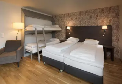 a bedroom with two bunk beds and a chair at Scandic Bakklandet in Trondheim