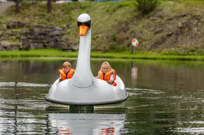 two children are sitting on a swan in the water at Hunderfossen Hotel & Resort in Hafjell