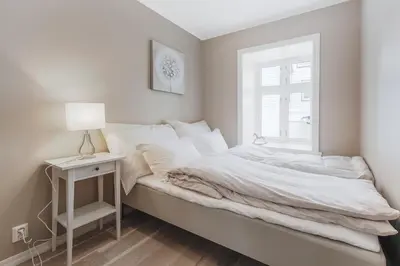a white bedroom with a bed and a window at Fosswinckel Apartments in Bergen