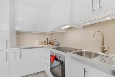 a white kitchen with white cabinets and a sink at Fosswinckel Apartments in Bergen