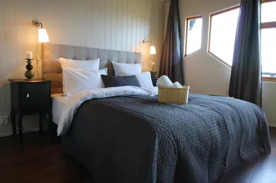 a bed with a blue blanket and a basket on it at Brekkestranda Fjordhotel in Brekke