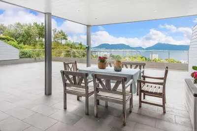 a table and chairs on a patio with a view of the water at Øyjorden Apartment in Bergen