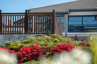 a balcony with red flowers in front of a house at Fitjar Fjordhotell in Fitjar