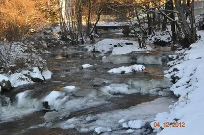 a stream with snow on the ground and a bridge at Fitjar Fjordhotell in Fitjar