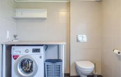 a bathroom with a washing machine and a toilet at Lovely Home In Valevåg With Wifi in Valevåg