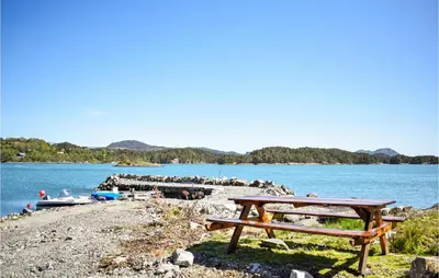 a picnic table on the shore of a lake at Lovely Home In Valevåg With Wifi in Valevåg