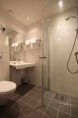 a bathroom with a shower and a toilet and a sink at Oppdal Turisthotell in Oppdal