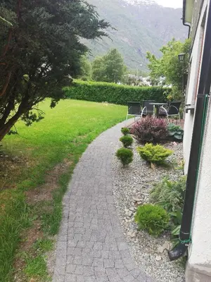 a walkway leading to a garden with chairs and plants at Apartment AliS in Tønjum