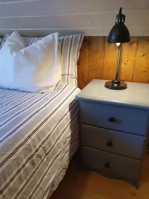 a bed with a nightstand and a lamp on it at Rugsund Handelsstad in Rugsund