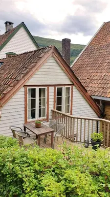 a house with a wooden deck with a table and chairs at Rugsund Handelsstad in Rugsund