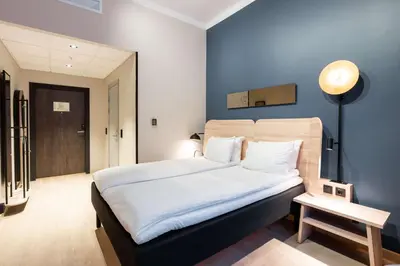 a bedroom with a large bed with a blue wall at Scandic Torget Bergen in Bergen