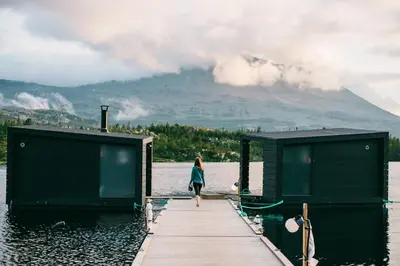 a woman walking on a dock on a lake with a mountain at Gaustablikk Fjellresort in Gaustablikk