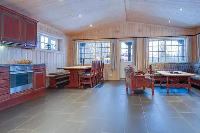 a kitchen with a table and chairs and windows at Knuts Hyttegrend in Beitostøl
