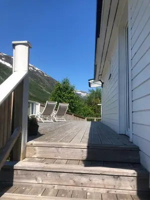 a wooden porch with chairs on the side of a house at Jølster Holiday home in Skei