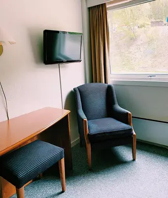 a room with a chair and a desk and a tv at Rødberg Hotel in Rødberg