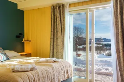 a bedroom with a bed and a large window at Grønolen Fjellgard in Beitostøl