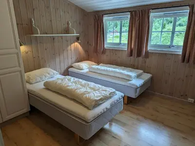 two beds in a room with two windows at Grønolen Fjellgard in Beitostøl