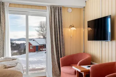a bedroom with a sliding glass door with a view of snow at Grønolen Fjellgard in Beitostøl