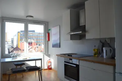 a kitchen with white cabinets and a table and a window at MB Apartments in Bergen