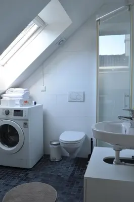 a bathroom with a toilet a sink and a washing machine at MB Apartments in Bergen