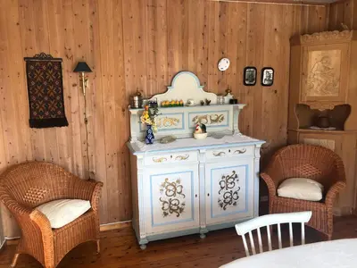 a white cabinet in a room with two chairs at Bakken Gårdshus in Rendalen