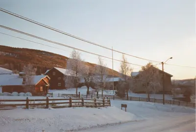 a snow covered village with a fence and buildings at Bakken Gårdshus in Rendalen