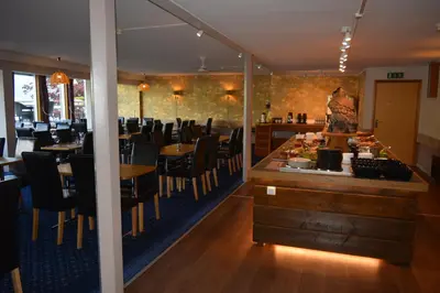 a restaurant with tables and chairs and a bar at Strand Fjordhotel in Ulvik
