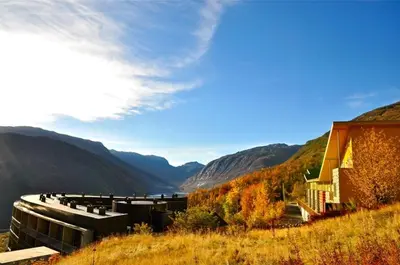 a building on a hill with mountains in the background at Hordatun Hotel in Røldal