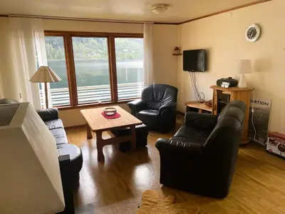 a living room with couches and a table and a tv at Der Fjordtraum in Balestrand direkt am Wasser in Balestrand