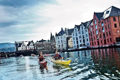 two people in kayaks on a river in a city at Kirkegata 4 in Ålesund