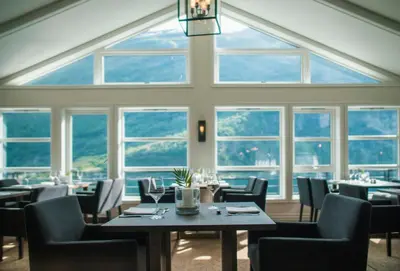 a dining room with tables and chairs and windows at Grande Fjord Hotel in Geiranger