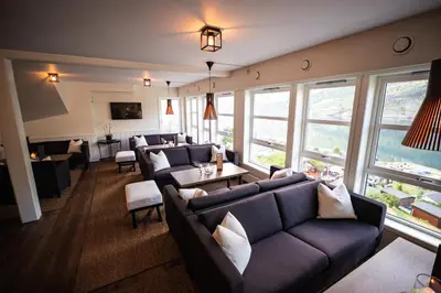 a living room with couches and tables and windows at Grande Fjord Hotel in Geiranger