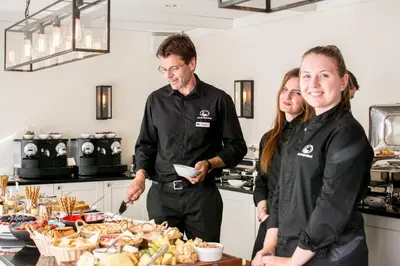 a man and two women standing in a kitchen with food at Grande Fjord Hotel in Geiranger